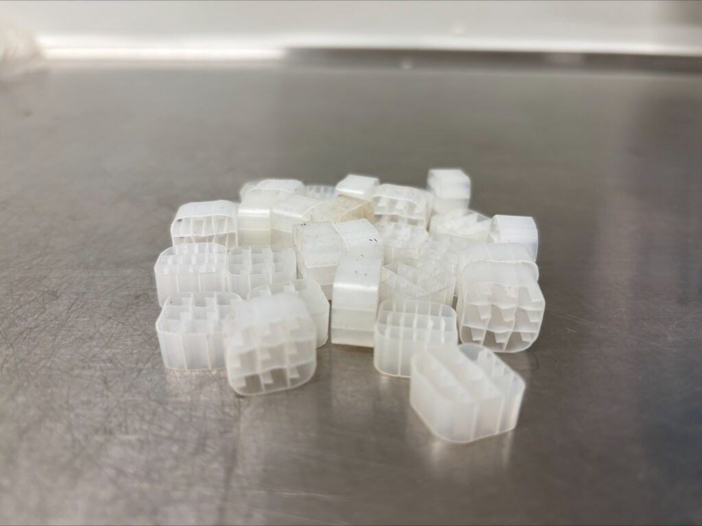 Eine Anordnung von kleinen, durchsichtigen Kunststoffkomponenten auf einer Edelstahloberfläche, die möglicherweise in einem biologischen oder chemischen Forschungsprozess verwendet werden.