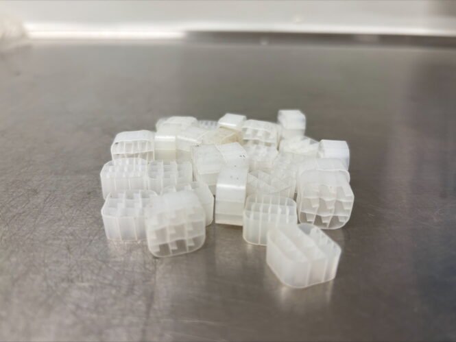 Kleine Kunststoffteile von Biowater Technology, so genannte Biofilmträger, die häufig in Wasser- und Abfallbehandlungssystemen eingesetzt werden. Sie bieten eine Oberfläche, auf der hilfreiche Bakterien wachsen und ihre Funktion effizient erfüllen können. Bild: Lu Feng