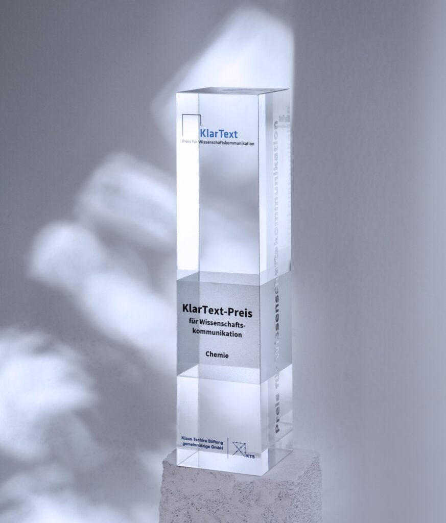 Transparente Auszeichnung mit der Aufschrift 'KlarText-Preis für Wissenschaftskommunikation' in der Kategorie Chemie, auf einem hellen Untergrund.