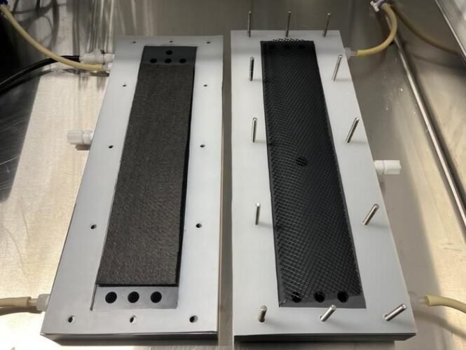 Two rectangular metal blocks with black textured inserts mounted on a metal base, each edged with metal pins around the perimeter.