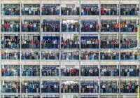 Large crowd of people on all floors of a multi-story office building, posing for a group photo.