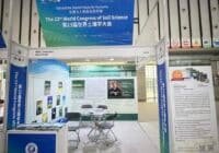 Exhibition booth for the 23rd World Congress of Soil Science with blue banners, posters, and a small seating area inside a hall.