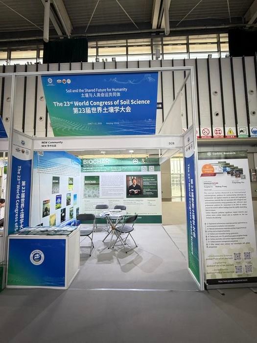 Exhibition booth for the 23rd World Congress of Soil Science with blue banners, posters, and a small seating area inside a hall.