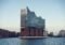 Elbphilharmonie concert hall with a wavy glass facade rising from a brick base by Hamburg harbor, reflected in the water.5c2 The iconic Hamburg building with a glassy, curved roof on the riverfront.5c2