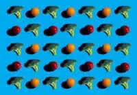 Repeating grid of broccoli florets and small orange and red tomatoes on bright blue background.