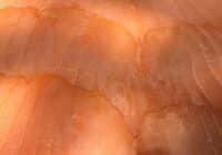 Close-up of orange-tinted human skin with deep wrinkles and fine lines under bright light.