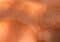 Close-up of orange-tinted human skin with deep wrinkles and fine lines under bright light.
