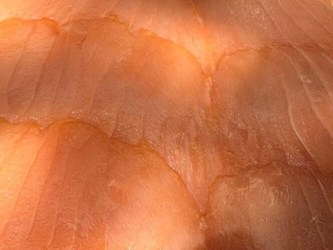 Close-up of orange-tinted human skin with deep wrinkles and fine lines under bright light.