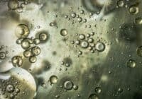 Bubbles of varying sizes suspended in a cloudy liquid with greenish-gray tones.