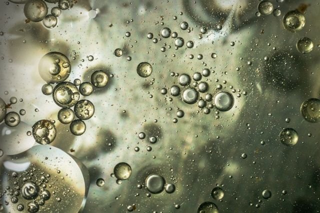 Bubbles of varying sizes suspended in a cloudy liquid with greenish-gray tones.