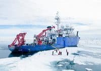 Arctic research vessel with red cranes on a cracked ice field and a small group of people inspecting the area