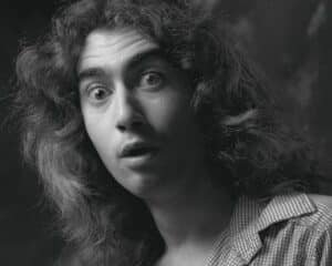 Black-and-white portrait of a woman with surprised expression, wide eyes, slightly open mouth, wearing a checkered shirt collar.