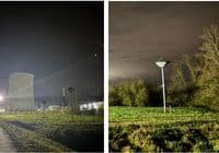 Night view of an industrial site with a tall cooling tower and bright floodlights.